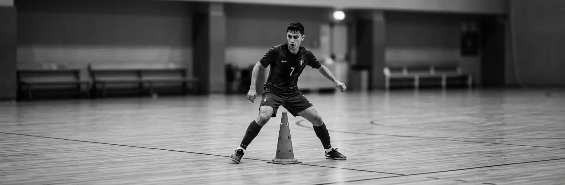 Futsal player training agility with cones on court