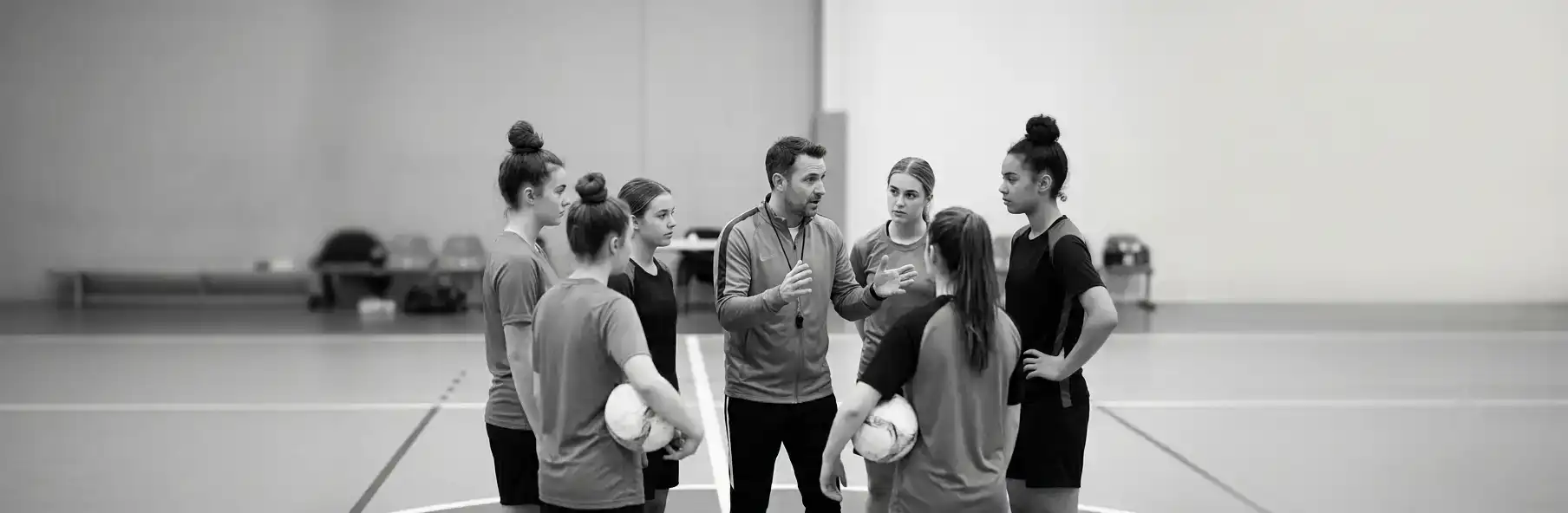 Futsal coach talking to the team gathered in a circle before training