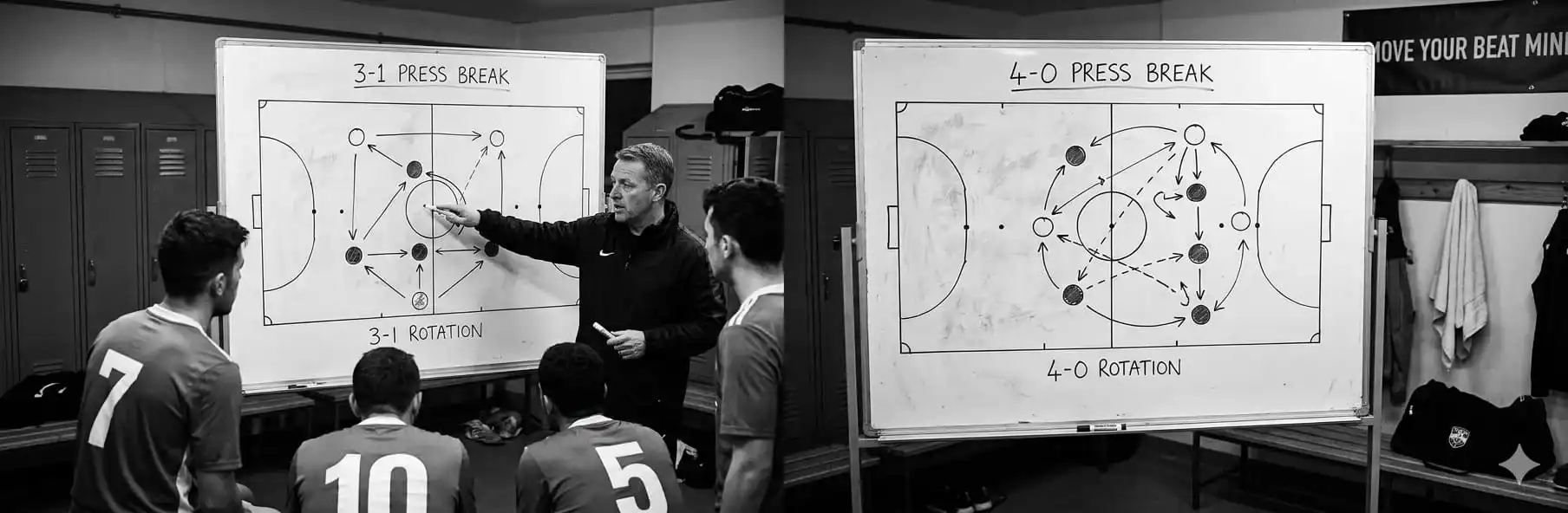 Futsal coach explaining a pressure exit routine on a tactical board before the match