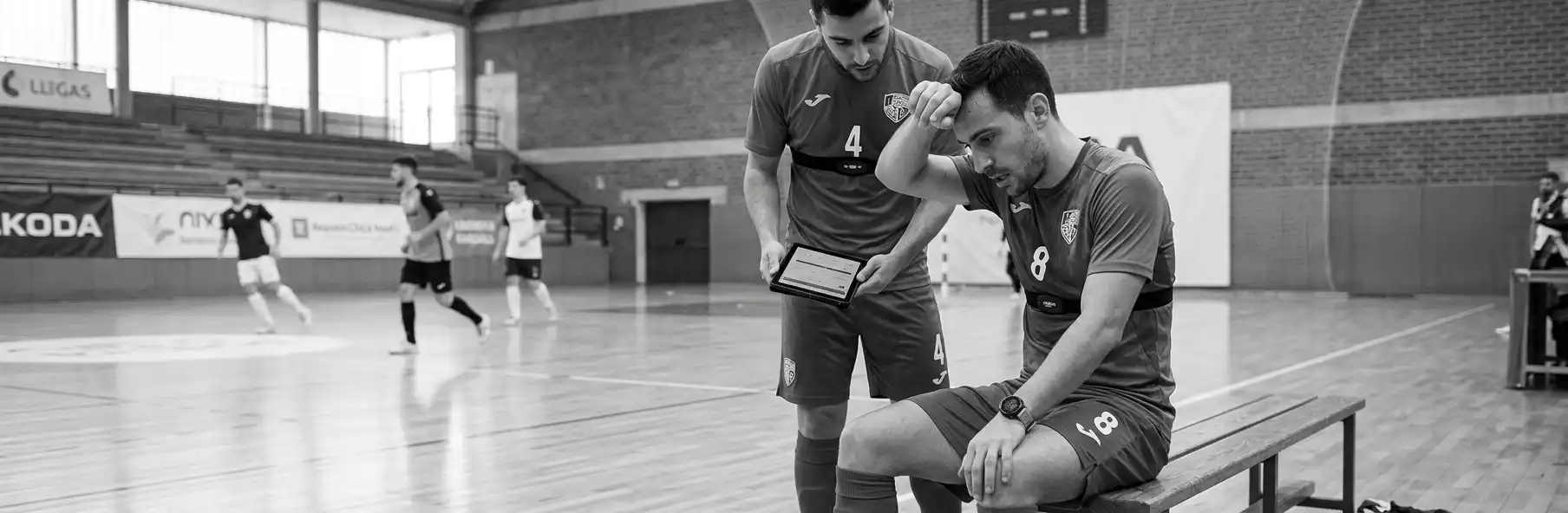 Futsal players on the bench wearing heart rate straps with a tablet showing each player's values