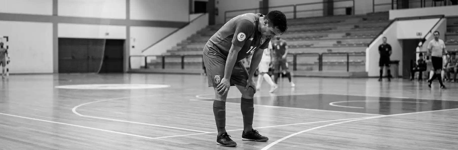 Futsal player bent over with hands on knees catching his breath during the game